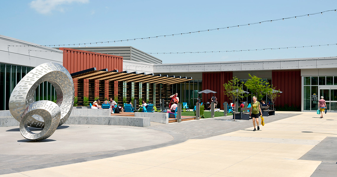 Entrance of the Merriam Community Center with people sitting in the courtyard.